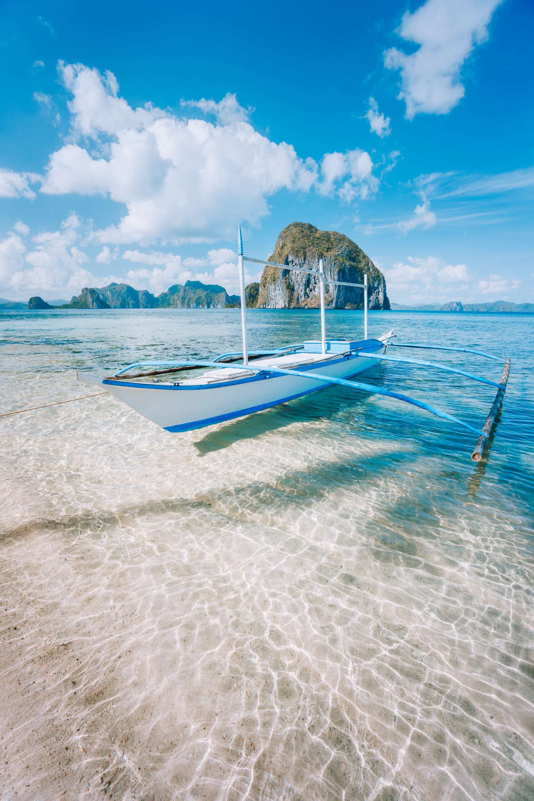 El Nido, Palawan, Philippines.<br />
Banca boat on sandy beach in shallow crystal clear water on island hopping trip.<br />
Amazing Pinagbuyutan island in background.<br />
Beautiful landscape scenery